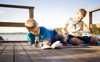 Två barn som läser böcker på en brygga